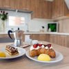 Tavolo con croissant, dolci e moka in cucina moderna.