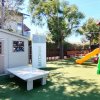 Un'area giochi all'aperto con scivolo arancione e casetta vicino a un cartello 
