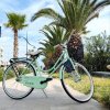 Una bicicletta verde chiaro parcheggiata su una passeggiata con palme.