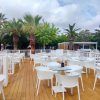 Una terrazza all'aperto con tavoli e sedie bianche, circondata da palme.