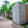 Un viale esterno con bungalow dai colori chiari e palme lungo il percorso.