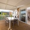 Terrazza coperta con tavolo e sedie in legno, vista su giardino e interni attraverso vetrata.