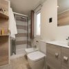 Bagno moderno con doccia in vetro, lavabo, bidet e finestra, rifiniture in legno chiaro.