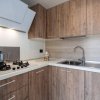 Cucina moderna con mobili in legno, piano cottura a gas, cappa bianca e lavello in acciaio inox.