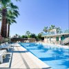 Piscina all'aperto con sdraio, palme e edificio con balcone.