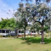 Giardino con alberi fioriti, prato curato e diversi edifici bianchi sullo sfondo.