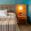 Letto con testata imbottita accanto a un comodino e lampada accesa.
