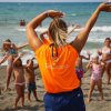 Animatrice e bambini fanno esercizi sulla spiaggia.