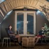 Due persone sedute davanti a una tenda glamping.