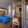 Interno con letto blu, tavolo e sedie.