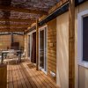 Veranda in legno coperta con tavolo e sedie di fronte a un bungalow.