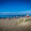 Spiaggia affollata con bagnanti e ombrelloni colorati.