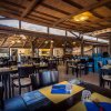 Un ristorante all'aperto con tetto di paglia, tavoli apparecchiati con tovagliette gialle e posate.