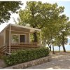 Una casa mobile moderna tra gli alberi, vicino a un lago.
