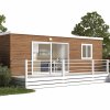 Casa mobile in legno con veranda bianca, immersa nel verde.