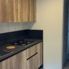 Cucina moderna con piano cottura nero e mobili in legno chiaro.