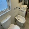 Un bagno con wc, bidet, lavandino rotondo, doccia e finestra.