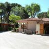Un piccolo edificio di mercato con tetto in tegole rosa, circondato da alberi e sedie fuori.