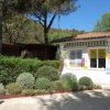 Una casetta bianca con cartelli informativi, circondata da siepi ben curate e alberi.