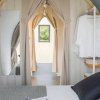 Interno di una camera accogliente con letto, specchio e vestiti appesi.
