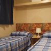 Due letti singoli con copriletti a quadri blu, lampada da tavolo al centro.