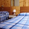 Due letti singoli con copriletti a quadri blu, pareti in legno.