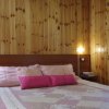 Camera da letto in legno con cuscini rosa e copriletto a quadri.