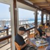 Persone sedute al bar di una spiaggia, vista sul mare.