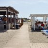 Pedana in legno tra due aree di ristoro sulla spiaggia.