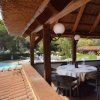 Terrazza coperta con tavolo apparecchiato, vista piscina.