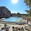 Piscina con lettini e ombrelloni colorati sotto un cielo azzurro.