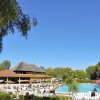 Piscina all'aperto con persone e edificio con tetto a paglia.