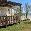 Veranda in legno affacciata su spiaggia sabbiosa con vegetazione.
