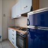 Cucina con frigorifero blu e mobili bianchi.
