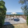 Terrazza con sedie e vista mare, incorniciata da arbusti.