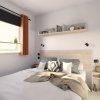 Camera moderna con letto, comodini e mensola.