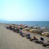 Una spiaggia con file di ombrelloni gialli e bianchi vicini al mare.