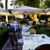 Tavoli all'aperto sotto grandi ombrelloni bianchi.