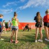 Gruppo di persone fa esercizi all'aperto su un prato sotto un cielo azzurro.